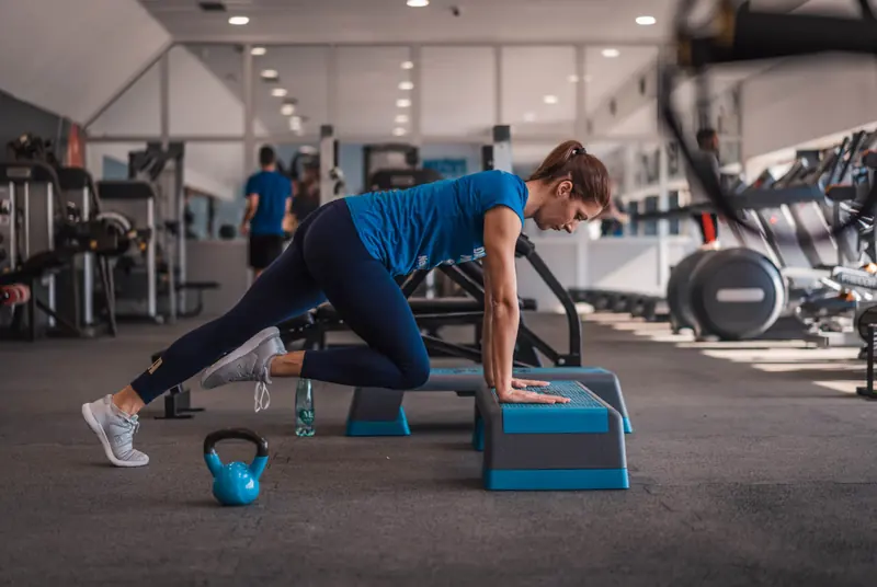 A woman performing a step-based functional exercise in a gym