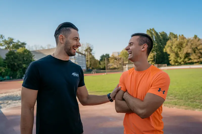 Two fitness trainers talking outdoors on an athletics track